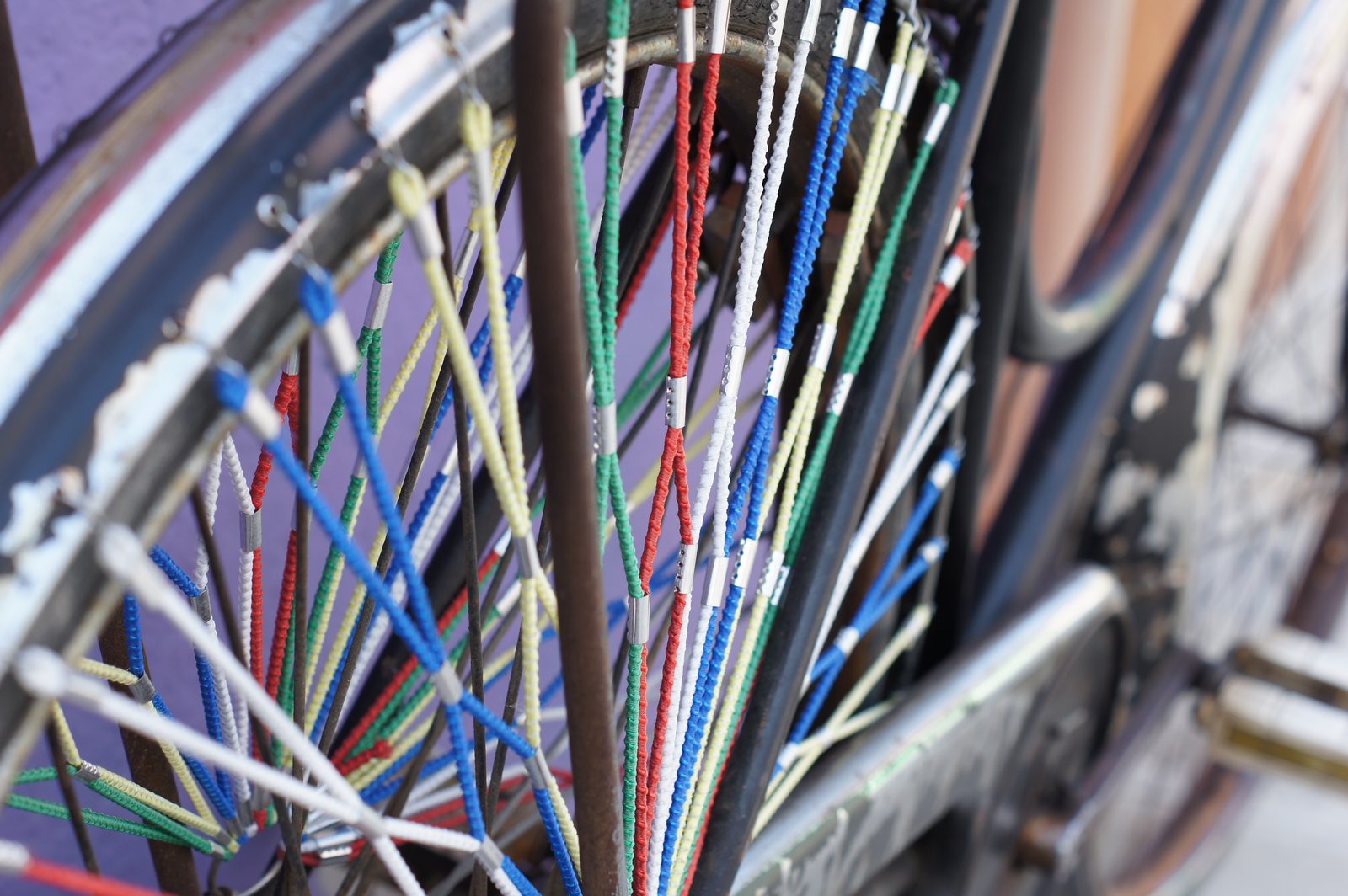 Bicycle wheel with colorful string threaded through the spokes